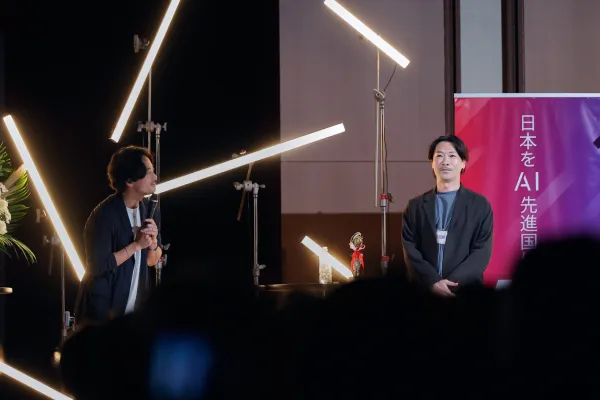 AI関連イベントのステージで、2名の登壇者が向かい合いながら来場者に向けて話している様子
