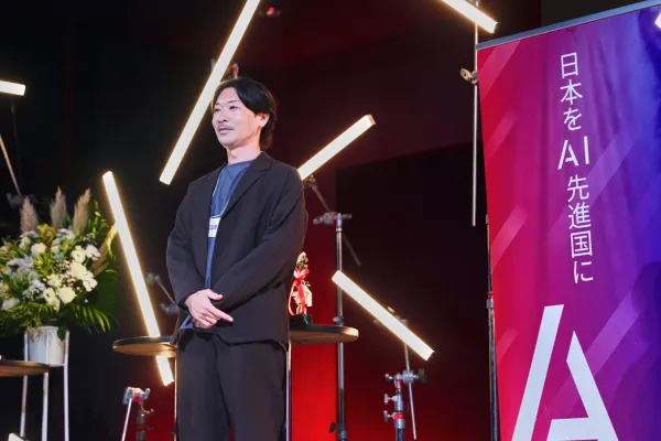 AI関連イベントのステージで、登壇者が壇上に立ち来場者に向けて話を聞いている様子