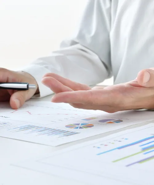 資料のグラフを前に、手振りを交えて説明しているビジネスシーンの様子